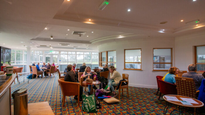A casual cafe or lounge area with people sitting in orange and brown chairs.