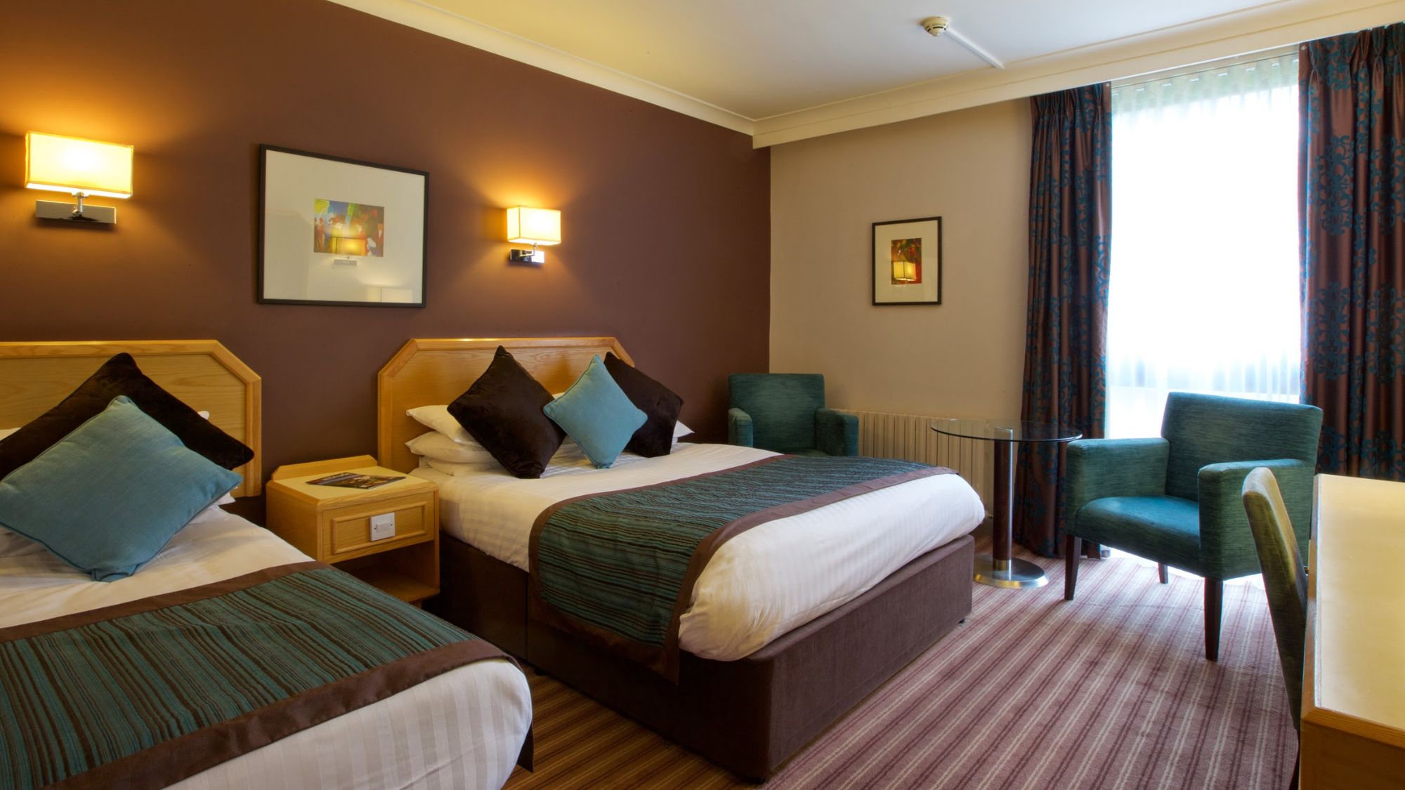 A spacious bedroom with a king bed and a small seating area.