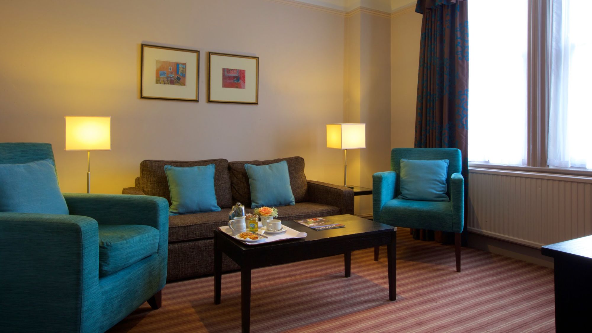 A suite featuring a separate lounge area with blue sofas and a coffee table.