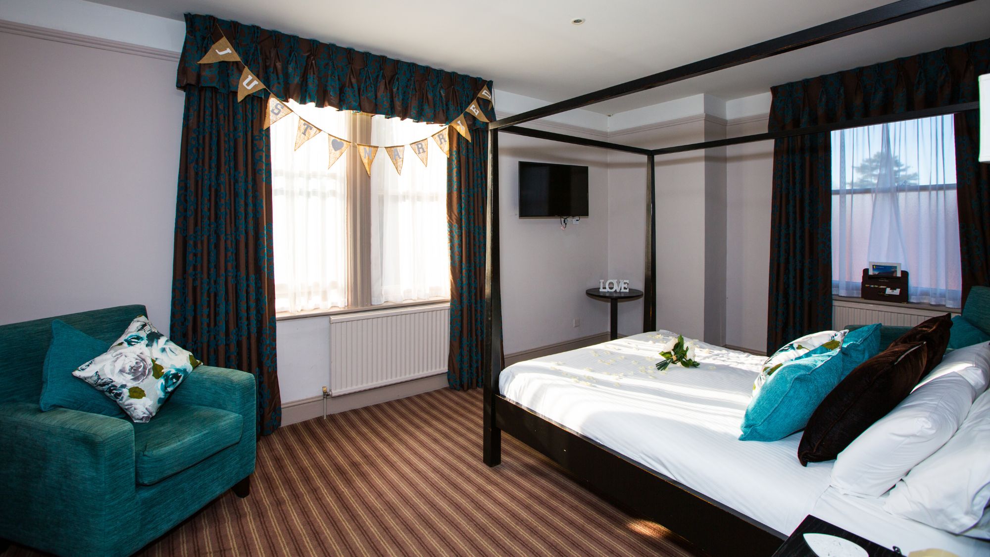A bedroom with a dark wood four-poster bed and white linens.