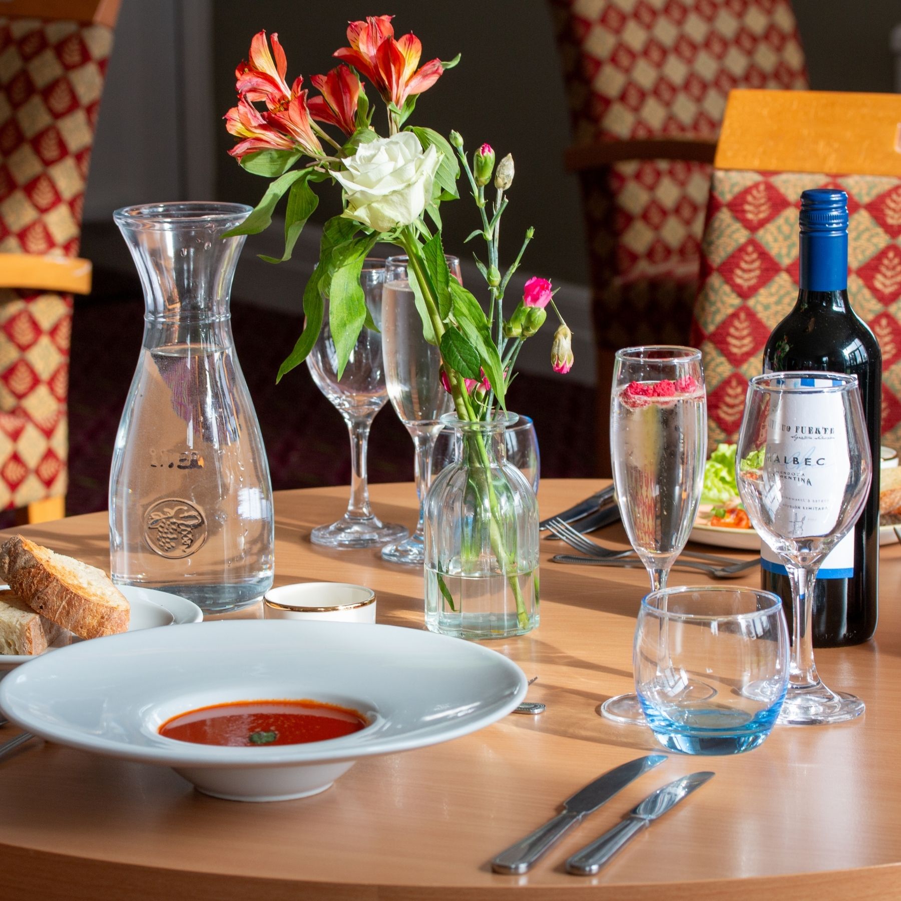 A formal dining table set for two with wine glasses and water carafes.