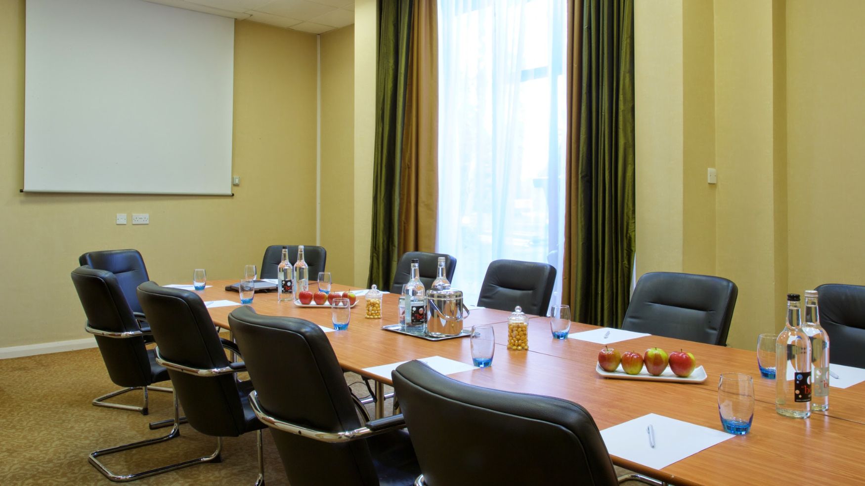 A conference room set for a meeting with black leather chairs and large windows.