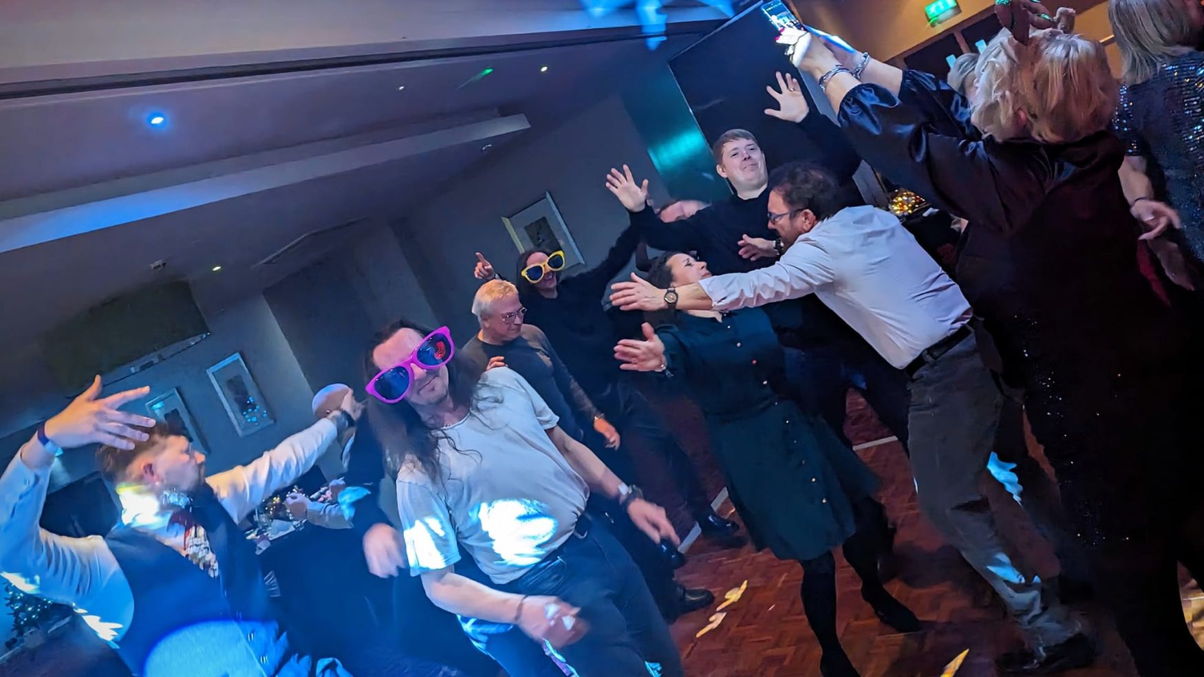 A group of guests dancing enthusiastically at a party or wedding reception.