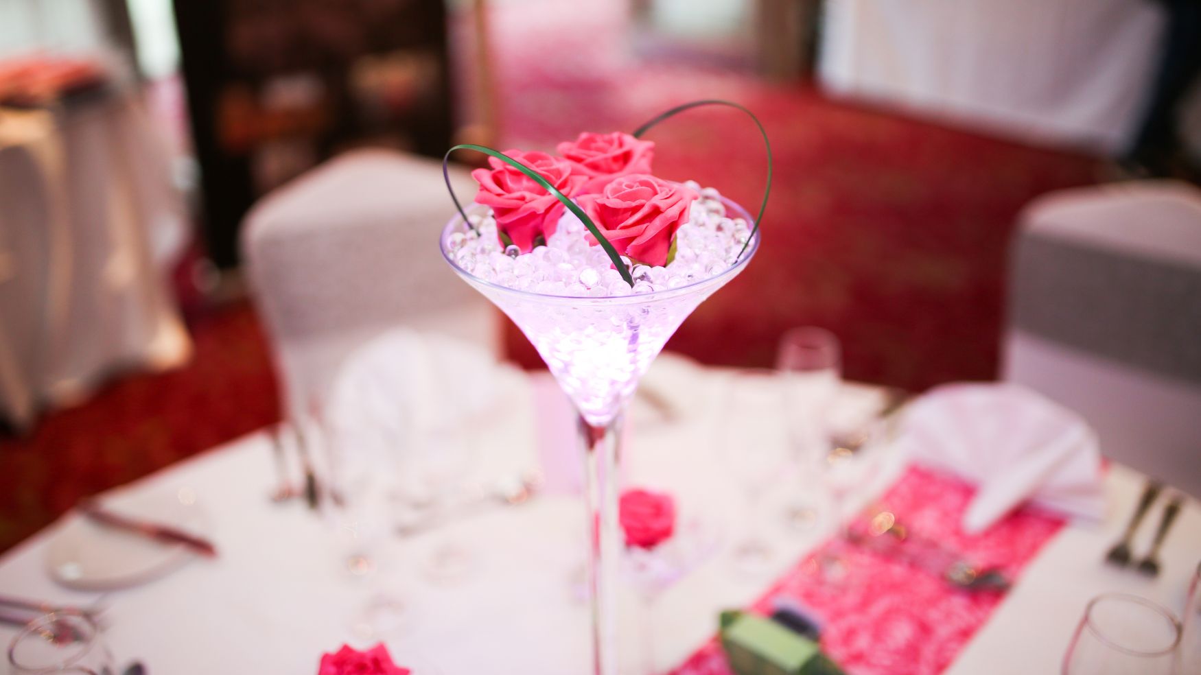 A close-up of a delicate pink floral centerpiece in a tall glass vase.